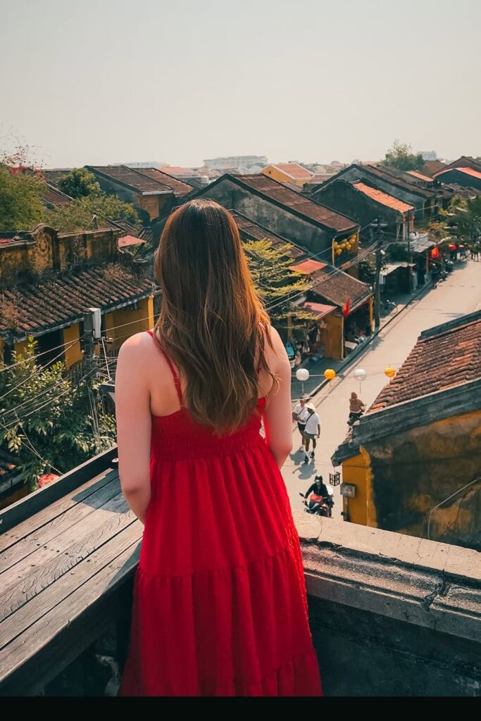 Woman in a red dress overlooking the rooftops of Hoi An Ancient Town from Faifo Coffee rooftop