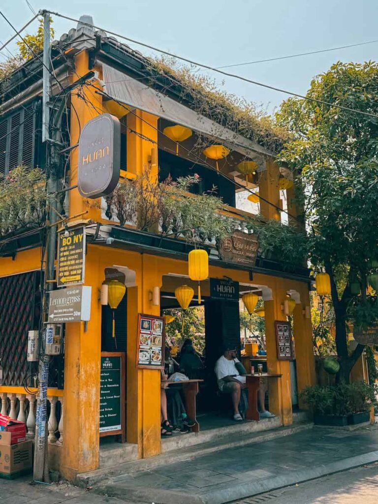Exterior of Uncle Huan Coffee in Hoi An Ancient Town with yellow walls and hanging lanterns