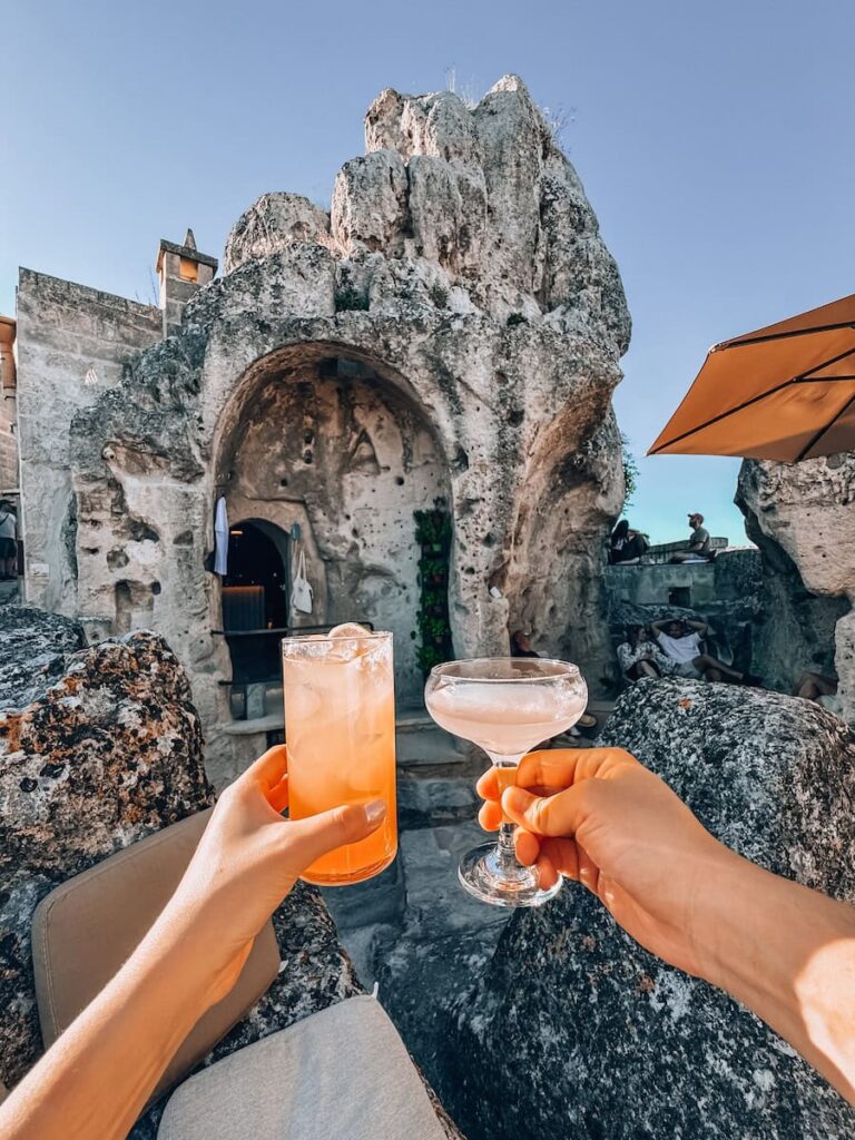 Cocktails served on the rocky outdoor terrace at Zipa Café in Matera, overlooking the ancient cave dwellings and dramatic limestone landscape of the Sassi.