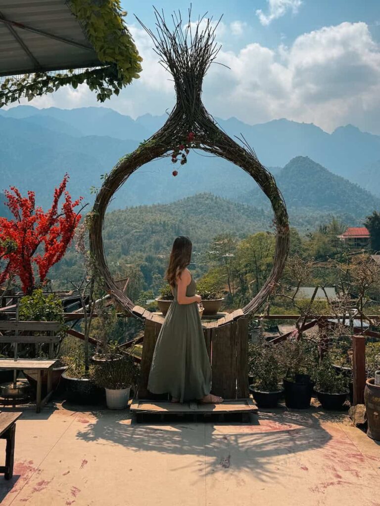 Scenic mountain viewpoint in Cat Cat Village near Sapa, Vietnam, featuring a large woven photo frame overlooking lush green valleys.