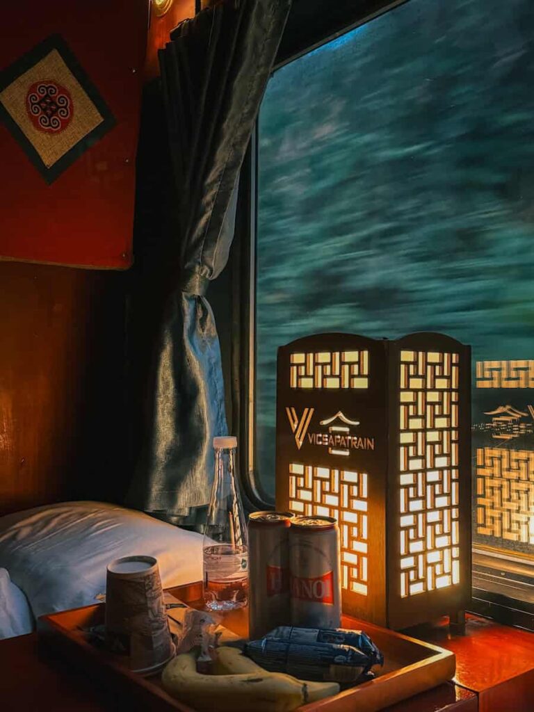 View from a private cabin aboard the VICSAPA overnight train from Hanoi to Sapa, with refreshments on a table beside the window as the countryside passes by.