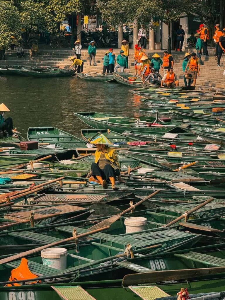 Wooden rowboats on the Ngo Dong River between limestone karsts at Tam Coc, Ninh Binh
