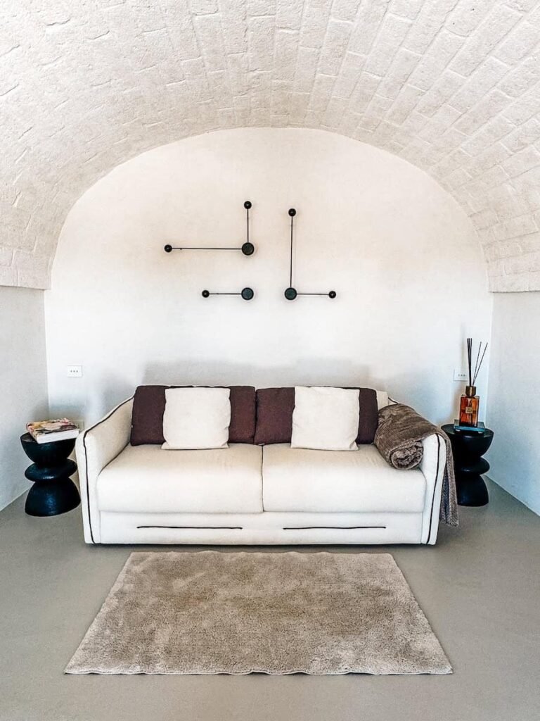 Living area of the White Loft suite at Trulli Damari with a white sofa under a vaulted stone trullo ceiling